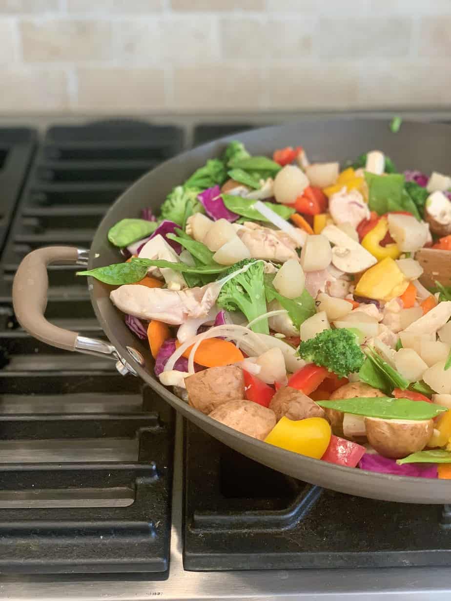 wok on stove with chopped vegetables in it.