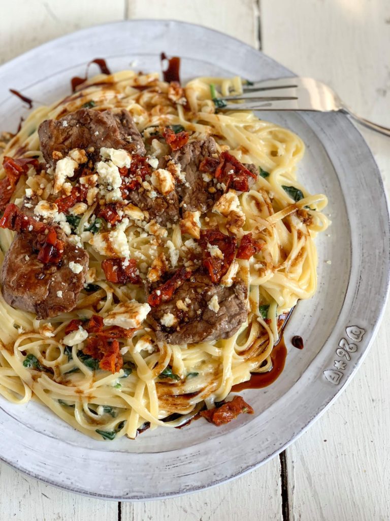 Steak Gorgonzola alfredo on a white plate and drizzled with balsamic reduction 
