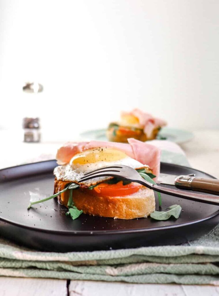 open faced egg sandwich on a plate. 