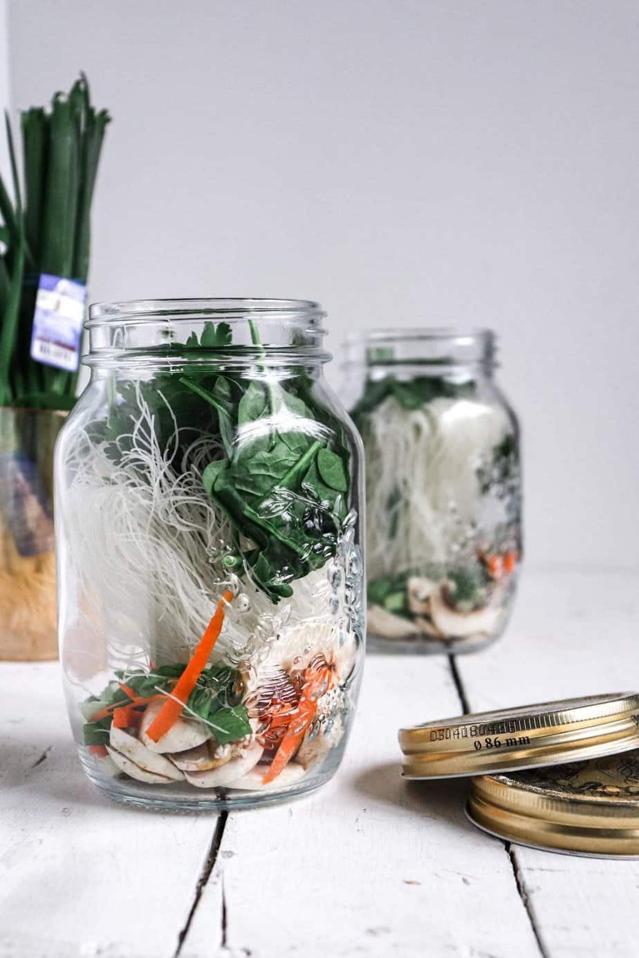 two glass jars with noodle cup ingredients added in.