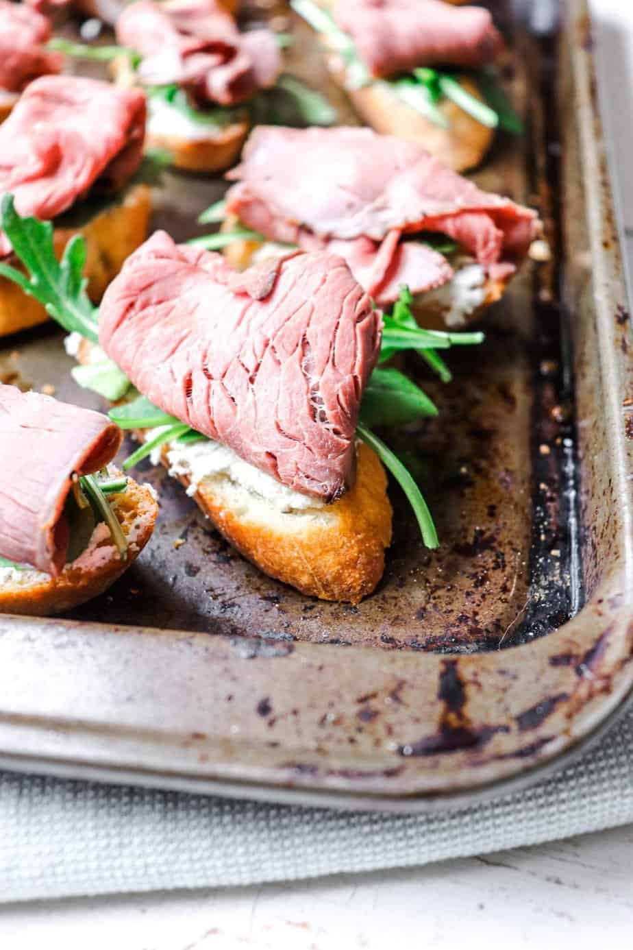 crostini on a baking sheet with one shown front and center