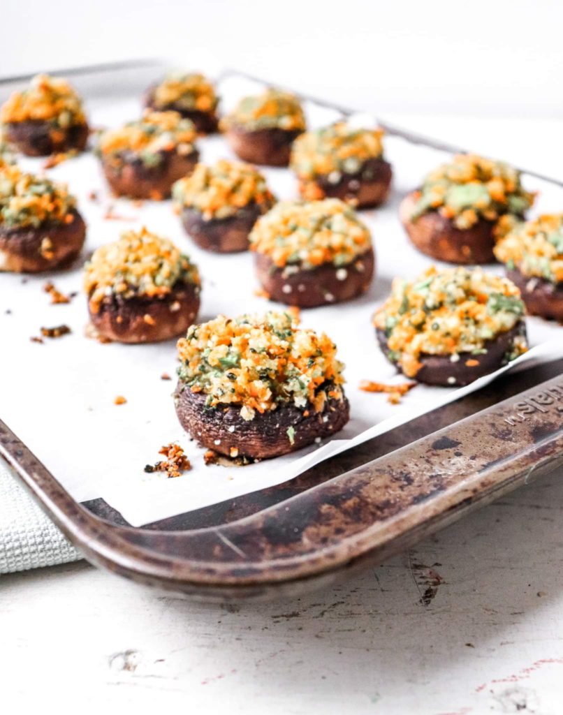 angled shot of stuffed mushrooms on a baking sheet.