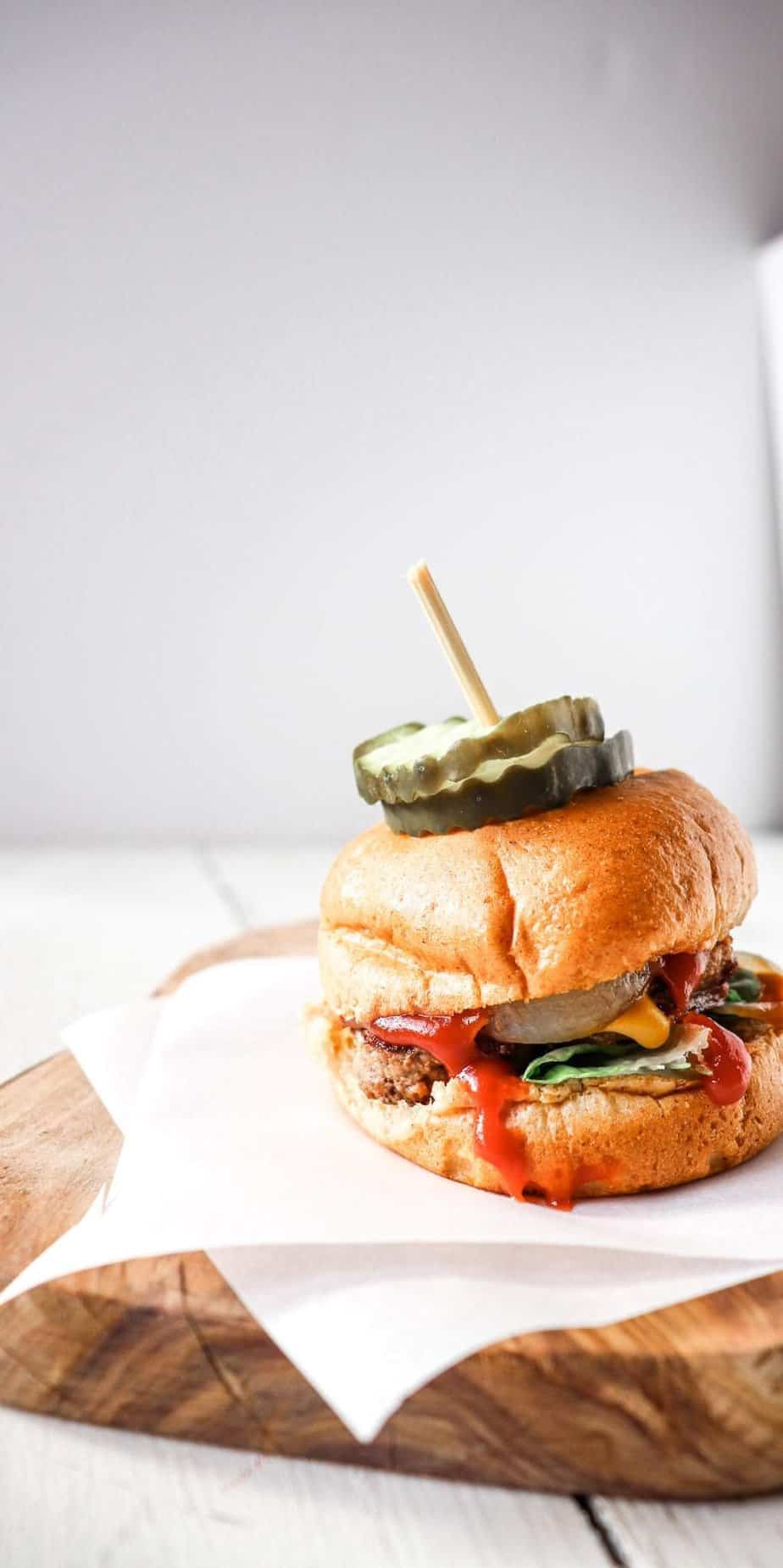 mini burger with onions and ketchup on a parchment lined board.