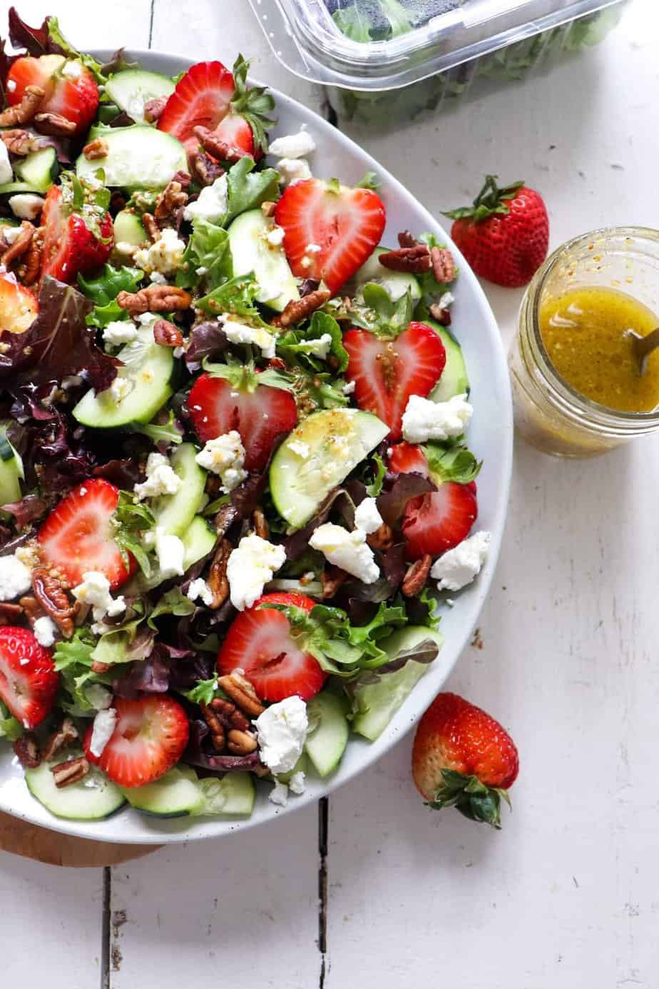 finished salad with mason jar of dressing to the side.