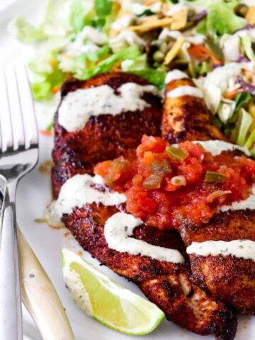 seasoned chicken breasts topped with salsa on a bed of salad.