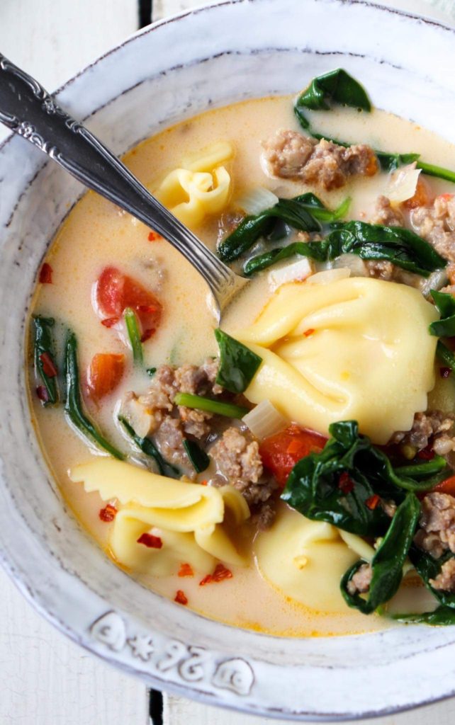 white bowl filled with tortellini with a spoon poking out