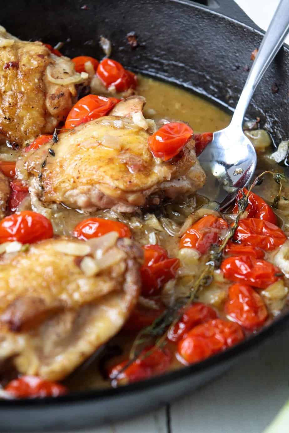 chicken thighs, tomatoes, and fennel, cooking in a cast iron skillet.
