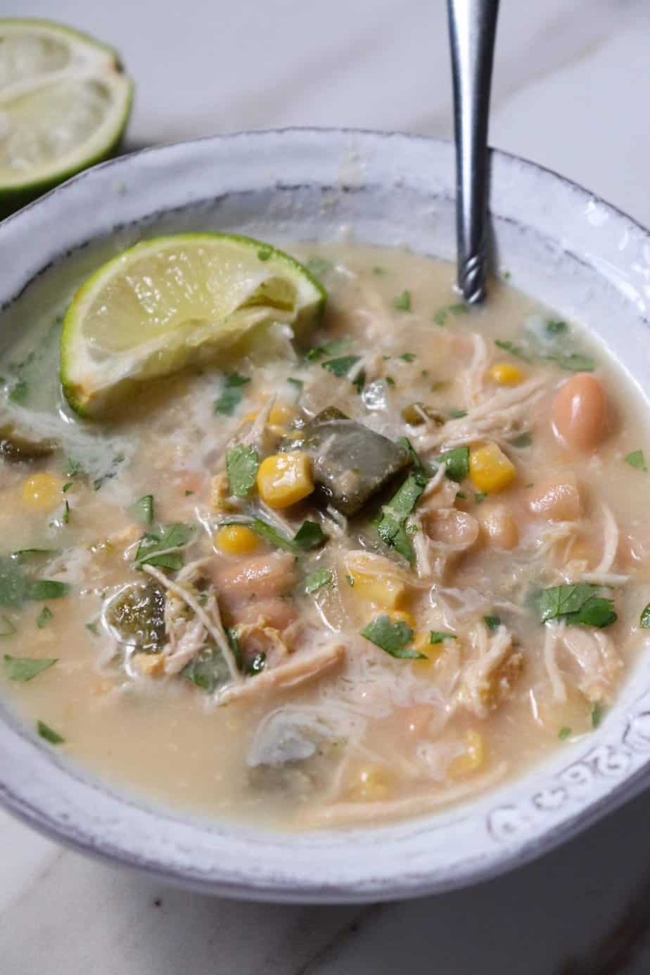 finished chicken and poblano soup in a bowl with a lime wedge.