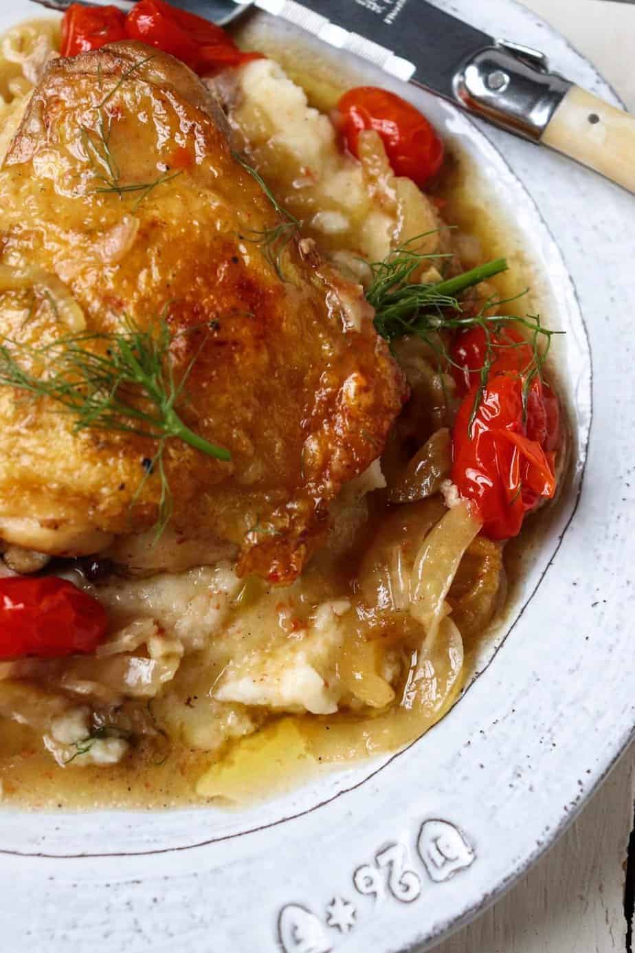 crispy chicken thigh plated on a bed of tomatoes and fennel.