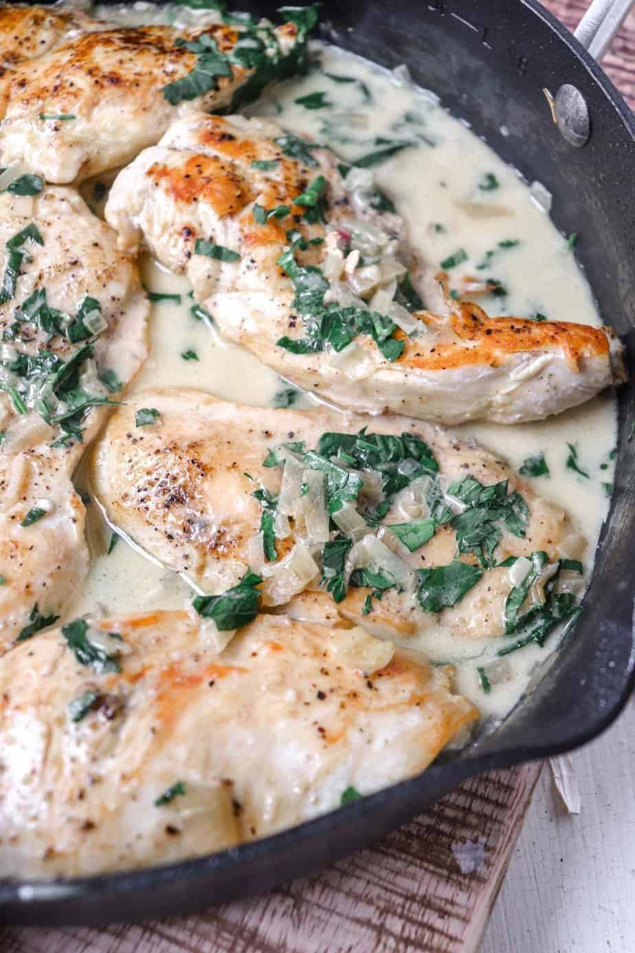 chicken breasts in pan filled with shallot sauce.