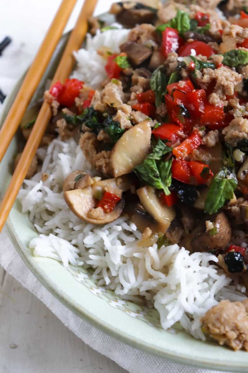 spicy basil chicken on rice with chopsticks close up
