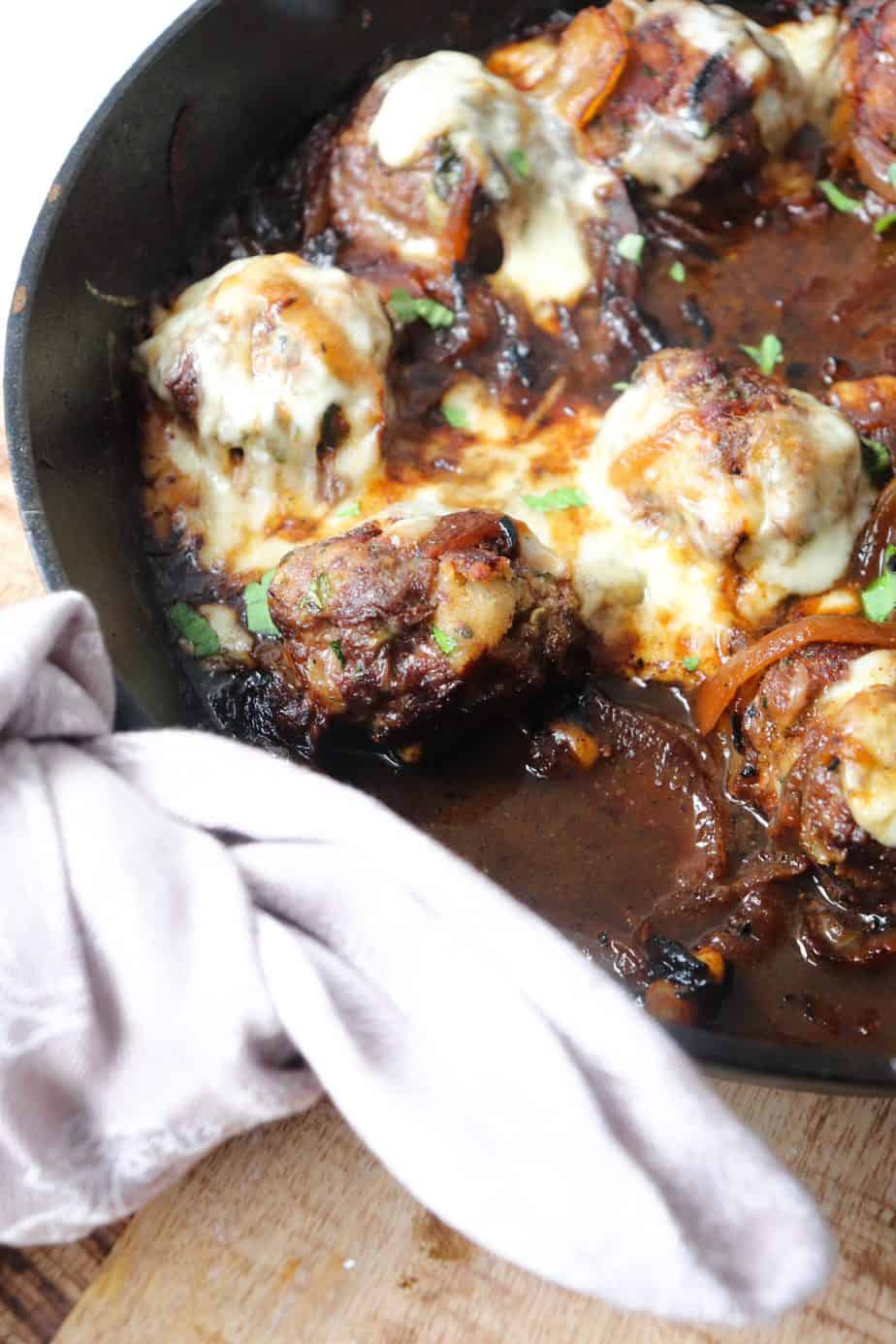 skillet full of meatballs and melted cheese.