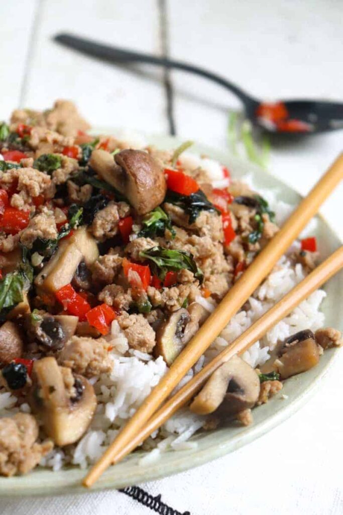 pad kra pao over rice in a flat green bowl