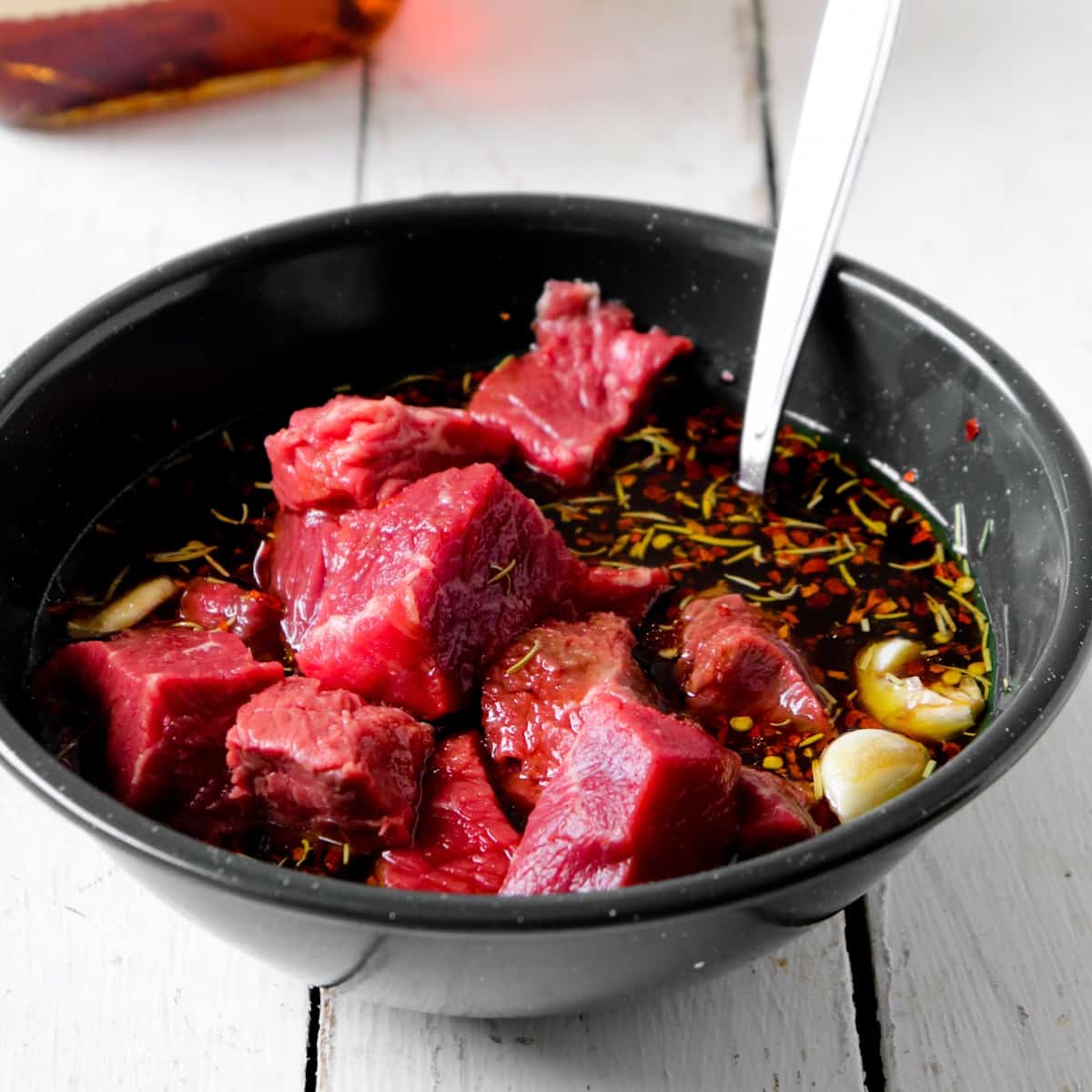 bourbon brown sugar marinade and beef pieces in a green bowl