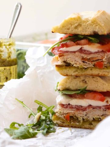 turkey pesto sandwich halves with pesto jar in the background.