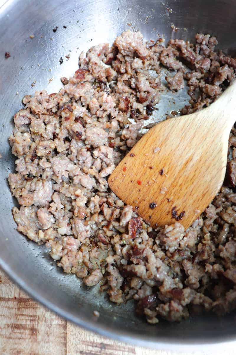 browning italian sausage crumbles in a pot.