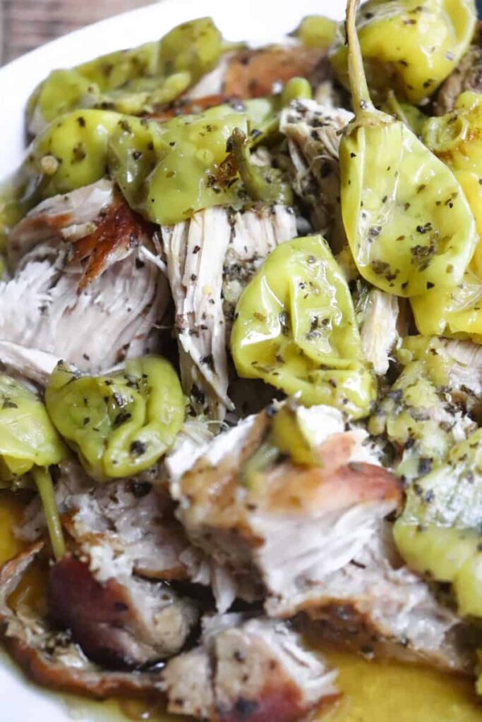 close up of shredded pork with pepperoncini pepers and spices