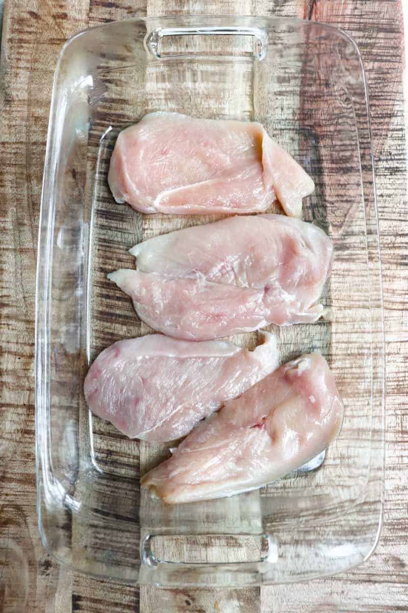 4 chicken breasts in a clear glass dish.