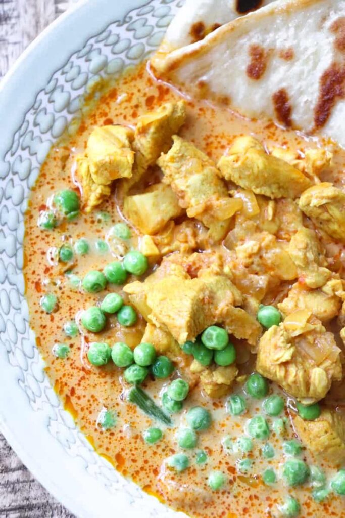 overhead shot of butter chicken with lots of peas