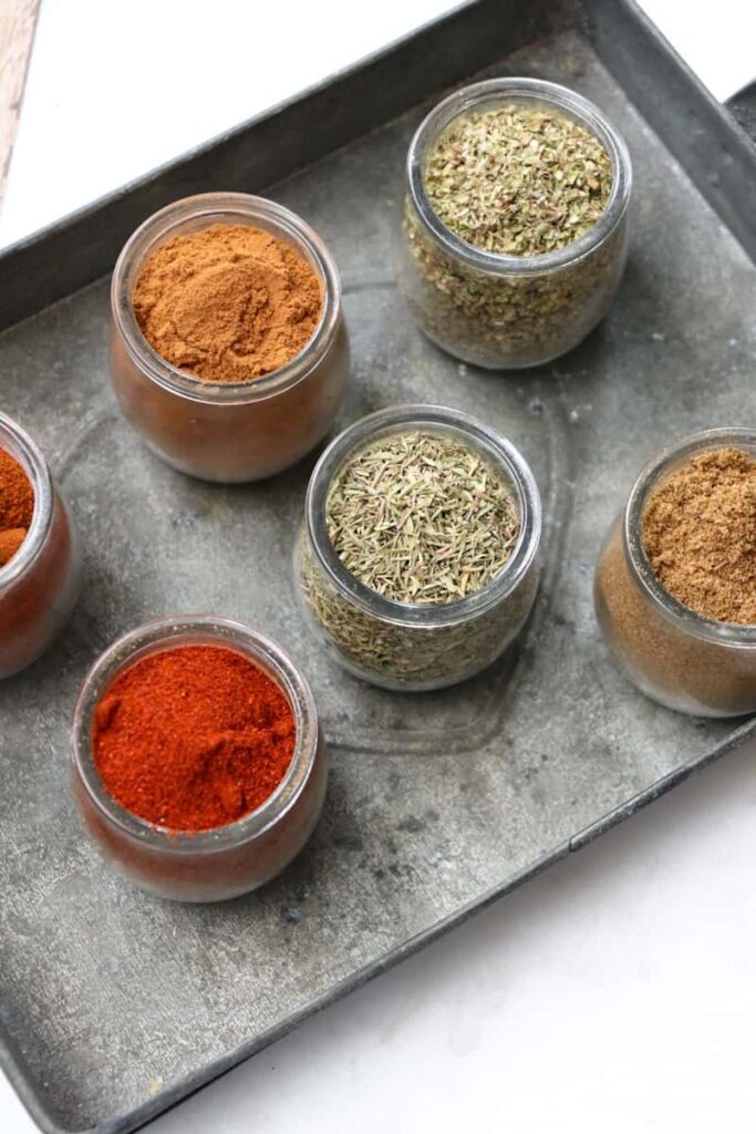 six classic spices in glass jars on a metal dish