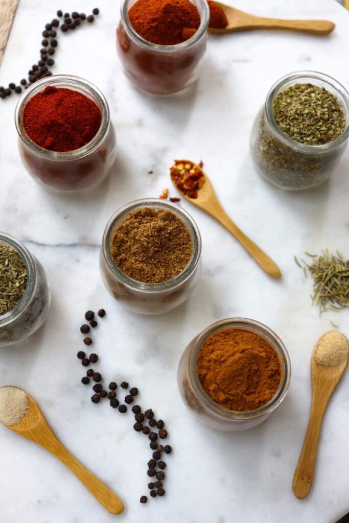 essential spices in glass jars placed decoratively on a white marble slab