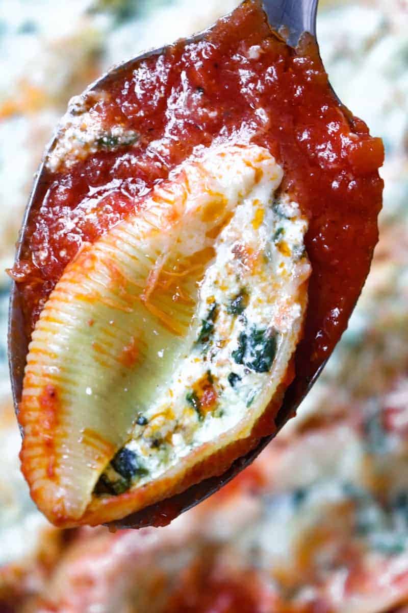 one stuffed shell and red sauce on a spoon close up