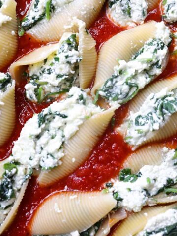 stuffed shells uncooked in sauce filled baking dish.