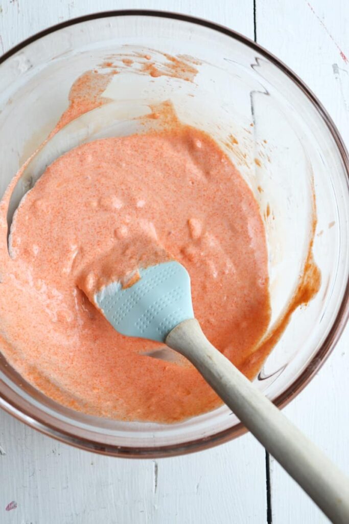 buffalo chicken sauce in a clear glass bowl with a spatula