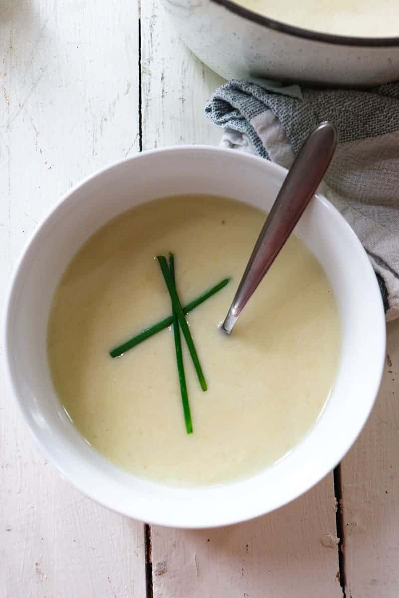 leek soup in a white bowl with chives criss-crossed on top