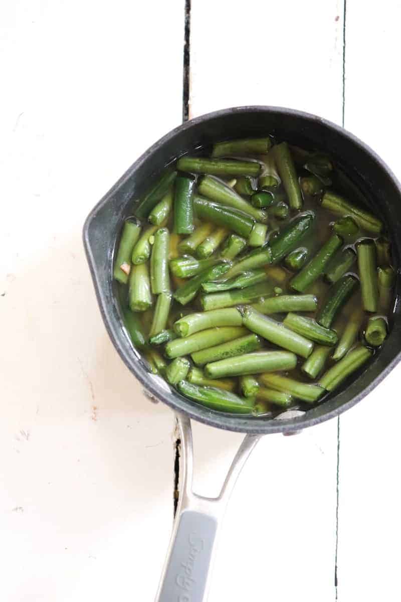 green beans in chicken stock in a small pot