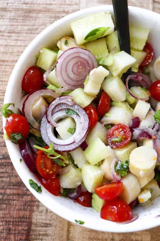 mixed salad in a white bowl with a black spoon 