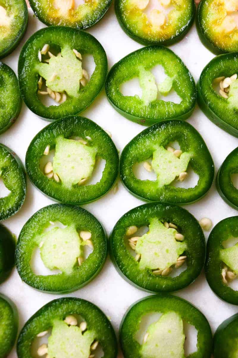thinly sliced jalapenos laying on a white background