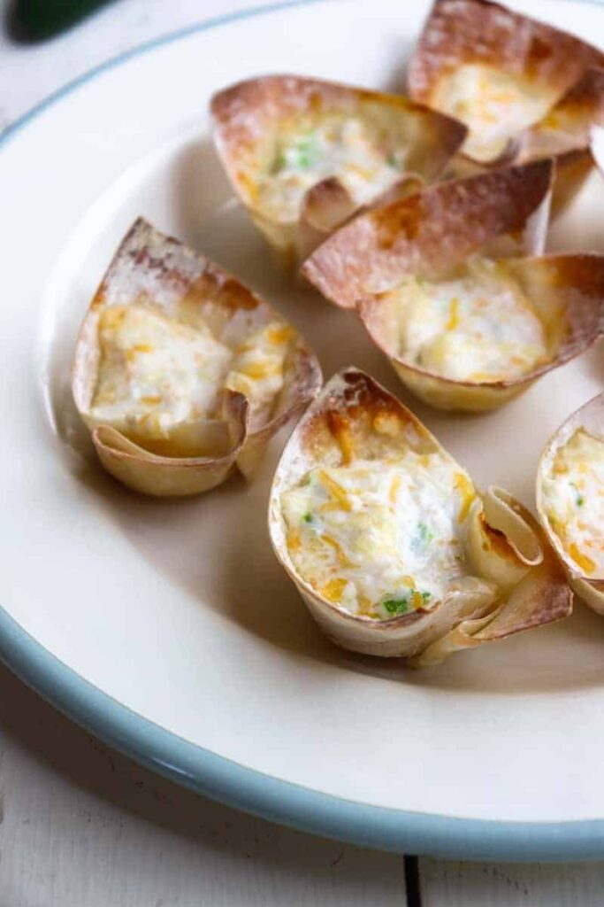 several jalapeno wonton cups on a white plate with a blue rim
