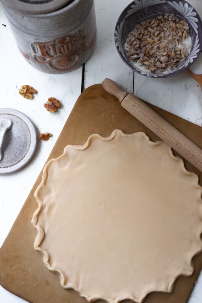 uncooked pie crust with a decorative edge and a rolling pin to the side