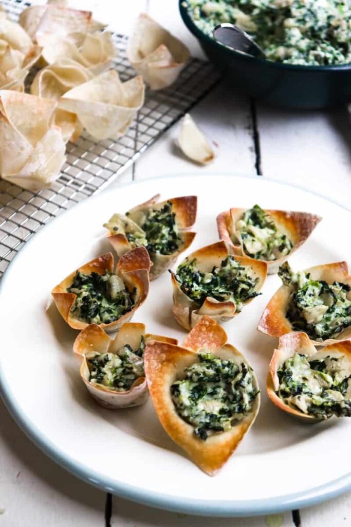 completed spinach bites on a white plated with the ingredients in the background