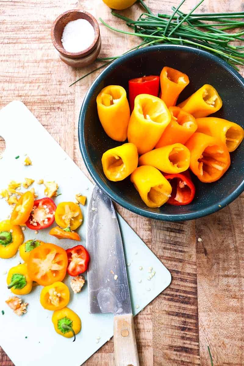peppers with tops cut off and a cutting board to the side