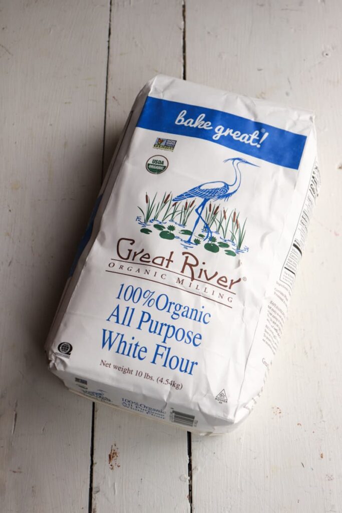 large unopened bag of flour on a white wooden table