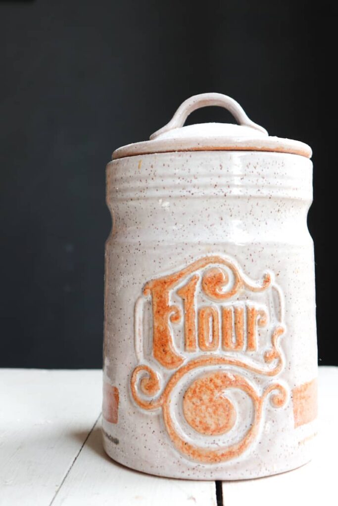 flour in a vintage ceramic canister that is labelled flour with orange lettering