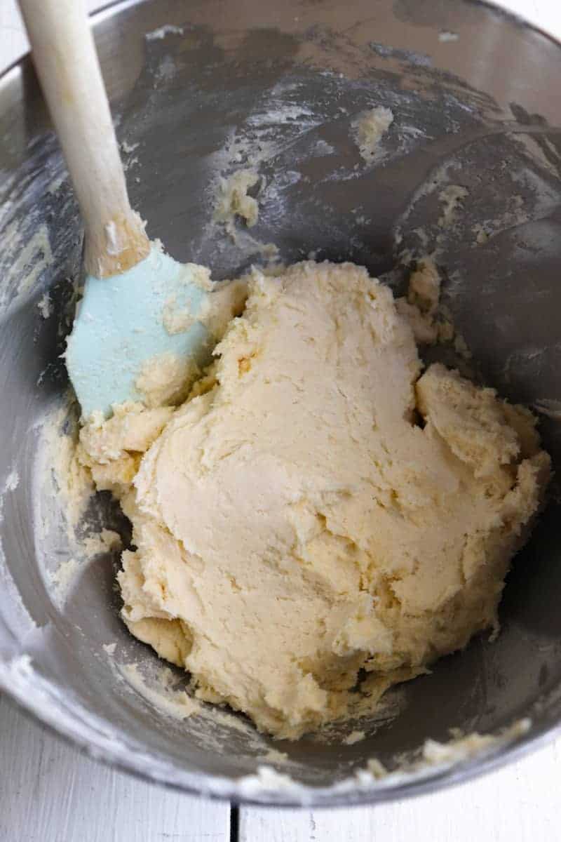 finished cream cheese kolacky dough in a stand mixer bowl with a blue spatula