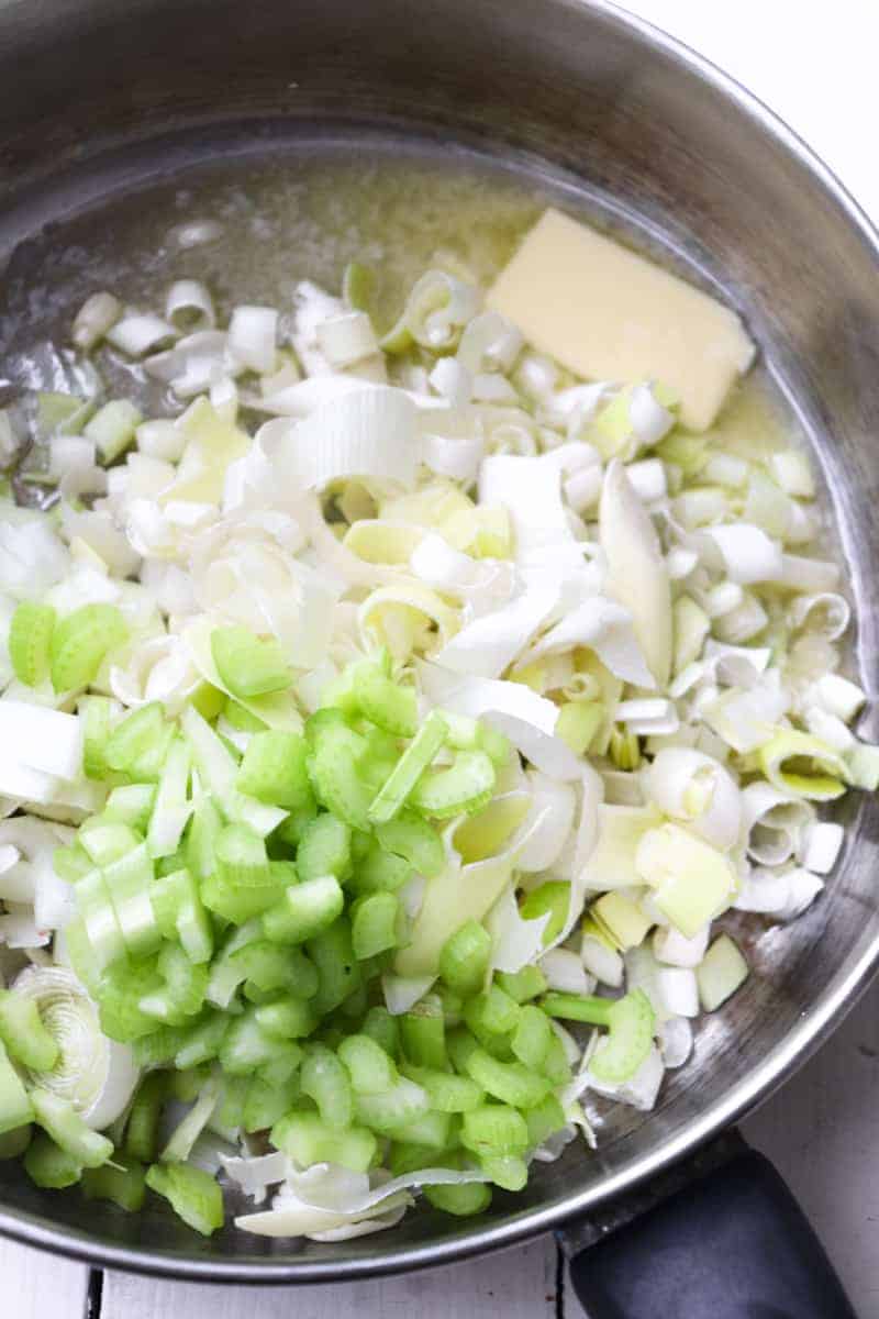 sliced leeks, diced onions, and celery in a pan with melting butter
