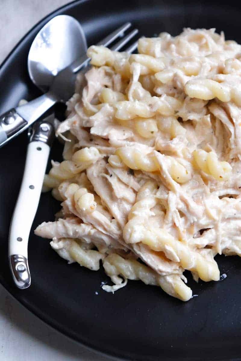 plated chicken pasta with silverware on a black plate