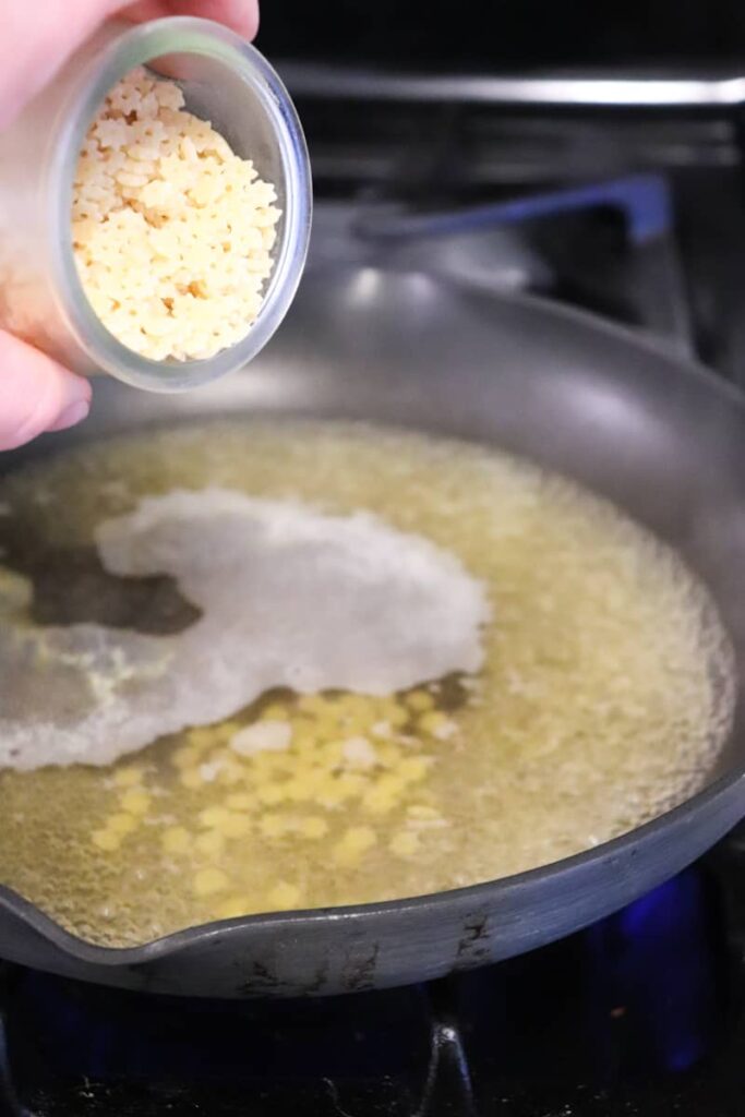 pasta being poured into simmering chicken stock