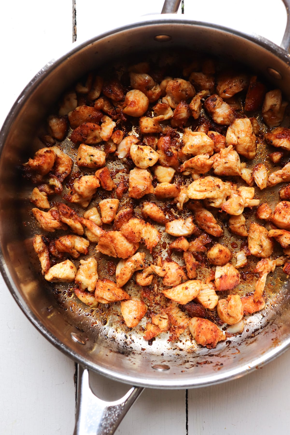 browned chicken pieces in a stainless steel skillet.