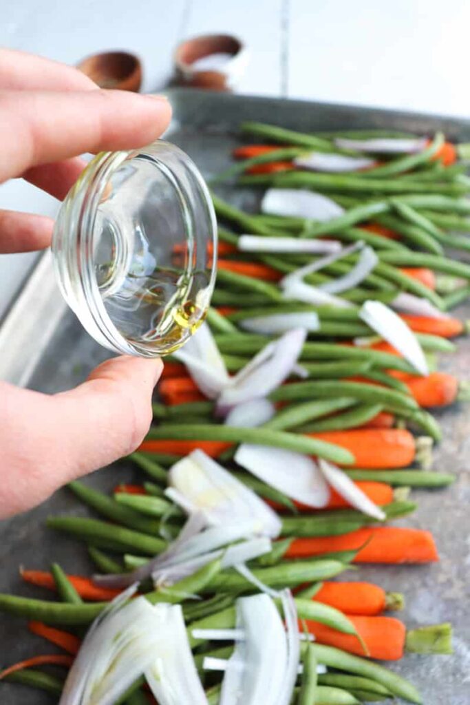 oil being poured on top vegetables for roasting