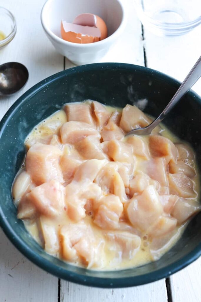diced raw chicken in an egg wash marinade 