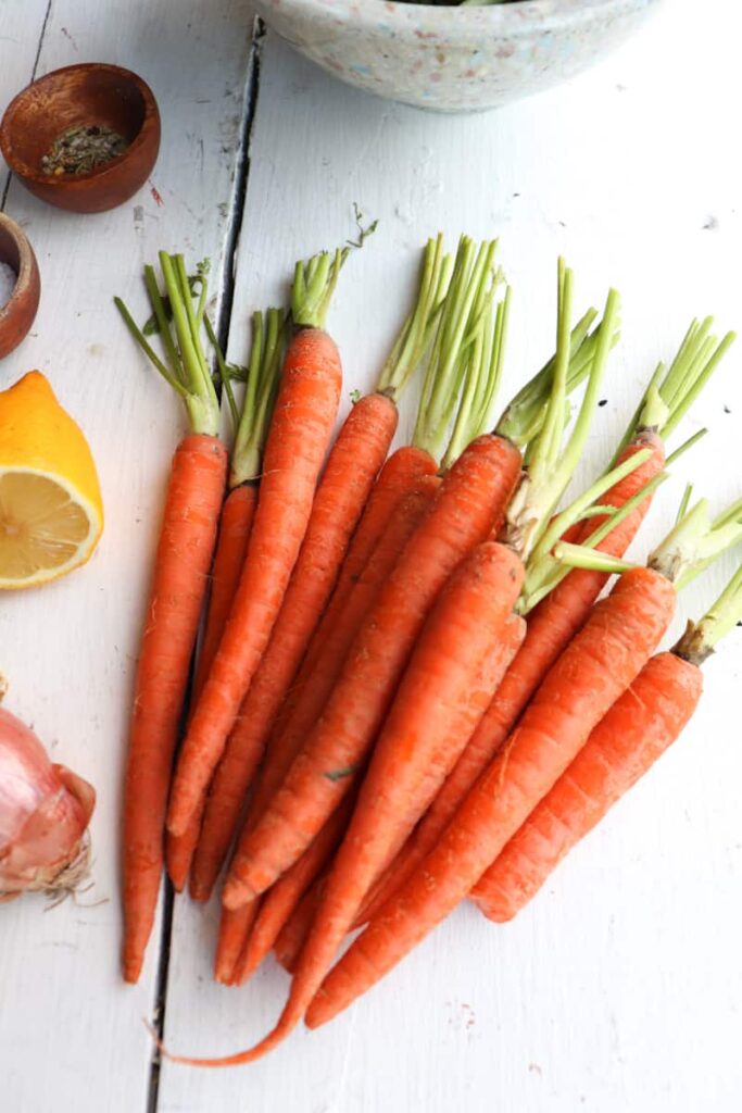ingredients for roasted vegetables on a white background with carrots being the main component