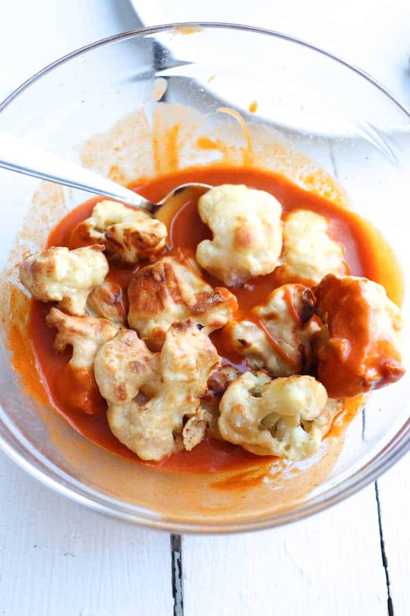 air fried cauliflower bites being tossed in buffalo sauce