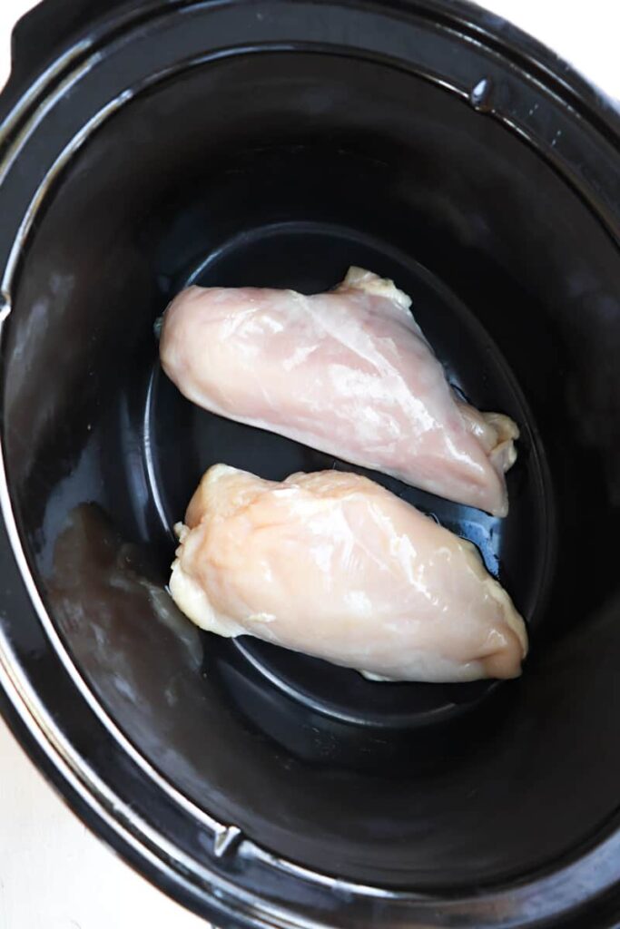 two chicken breasts in bowl of crockpot