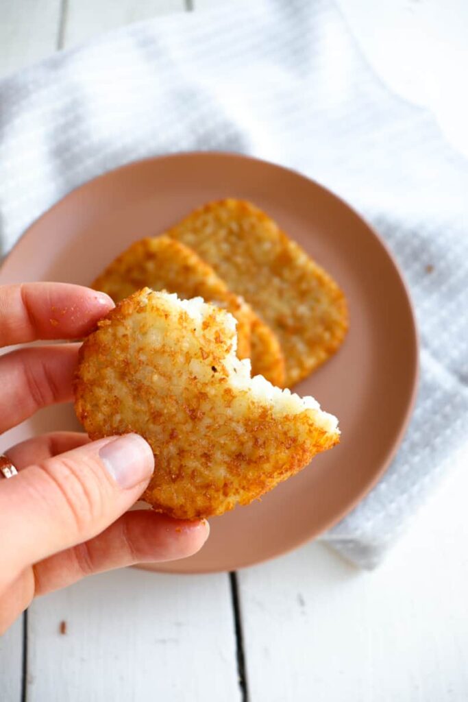 hand holding a half of hash brown pattie to show crispiness