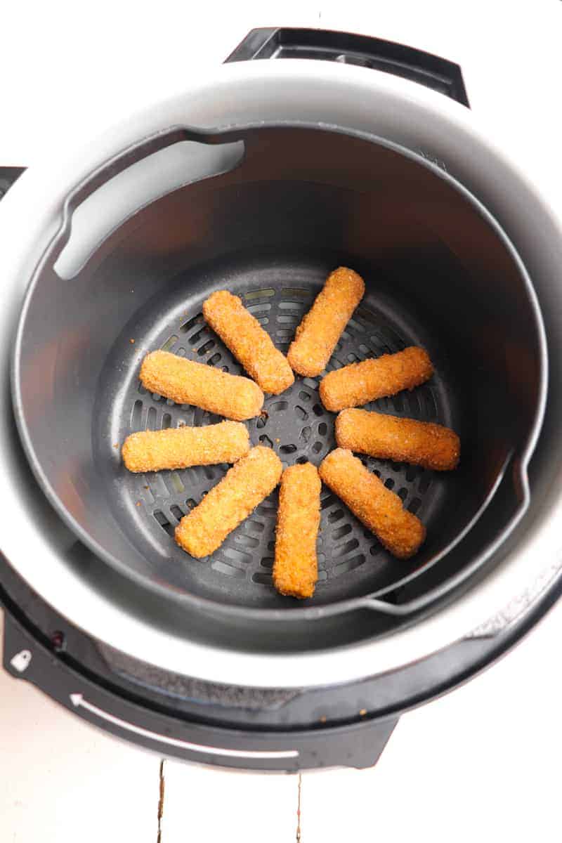 frozen mozzarella sticks arranged in air fryer basket